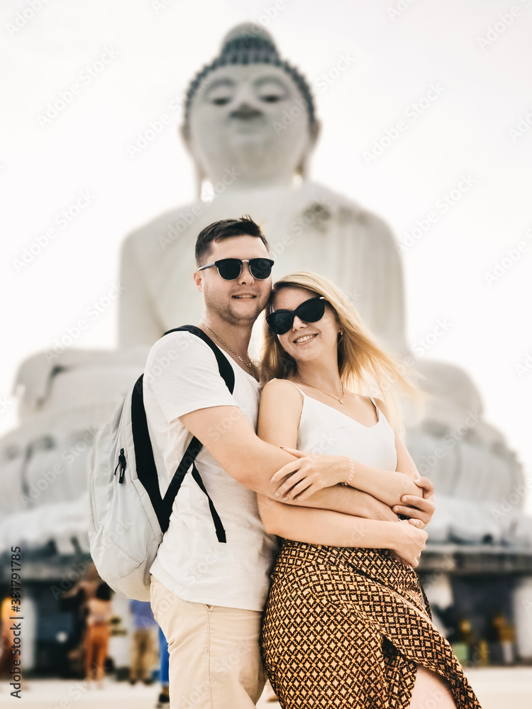 Tourists a man and a girl stand near big Buddha, Thailand