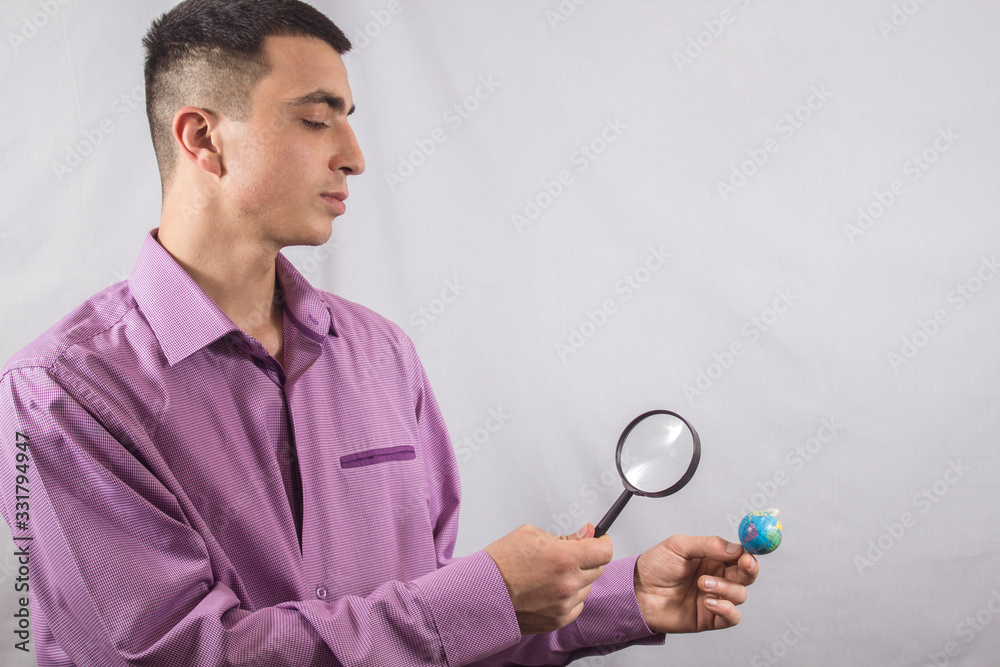businessman looks at a globe through a magnifier businessman looks at a globe through a magnifier