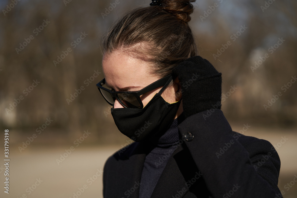 Young girl in a black protective mask and black sunglasses on the street, protecting against the virus Young girl in a black protective mask and black sunglasses on the street, protecting against the virus