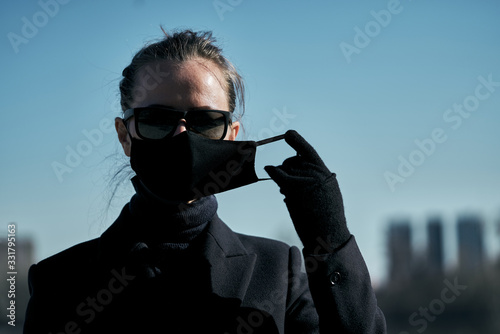 Young girl in a black protective mask and black sunglasses on the street, protecting against the virus photo