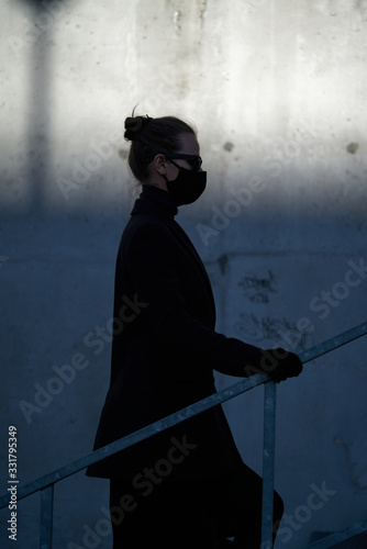 Young girl in a black protective mask and black sunglasses on the street, protecting against the virus