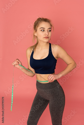 Beautiful slim young european woman measuring tape thin waist wear uniform fitness isolated pink background, european girl loss weight for diet with exercise and workout wellbeing and healthy care © Vasya
