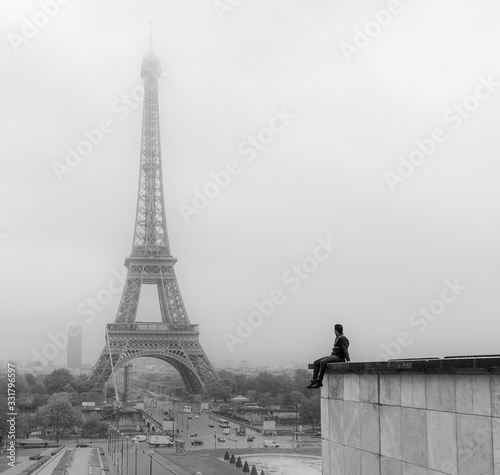 Fototapeta Naklejka Na Ścianę i Meble -  hombre joven sentado viendo torre eiffel en blanco y negro
