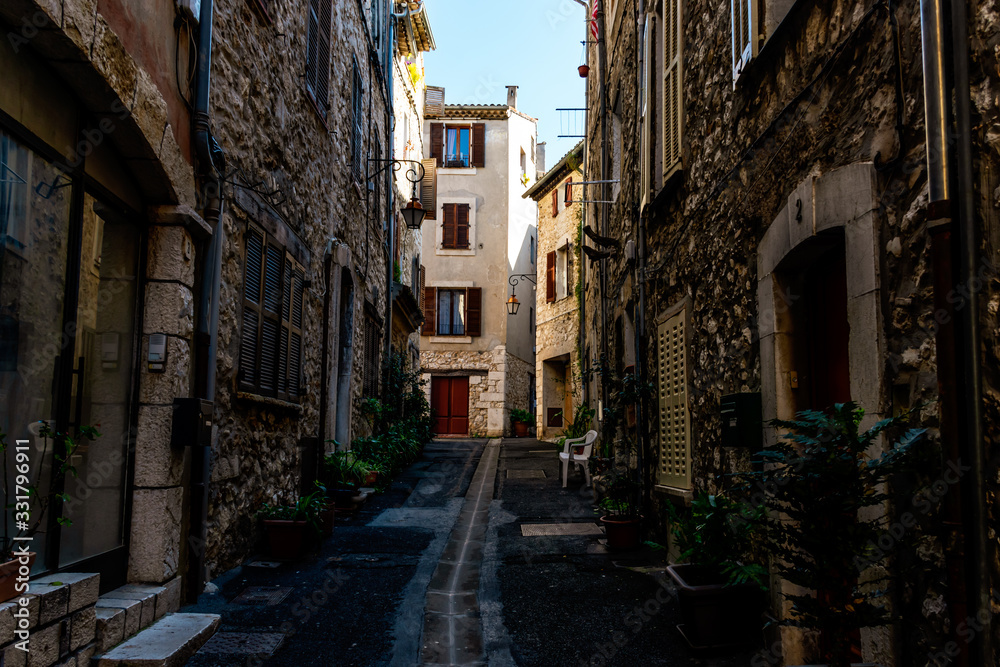 A narrow small street in the old medieval center of a French town in the morning after rain (Vence, France)
