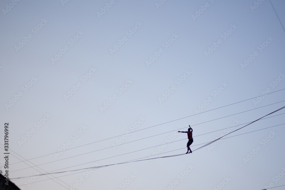 Man balancing on a rope against the sky Man balancing on a rope against the sky