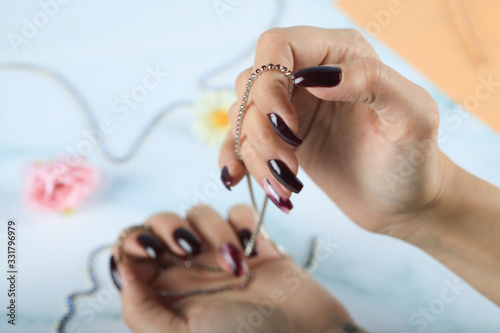 Well manicured  red nail polished woman hands holding a necklace