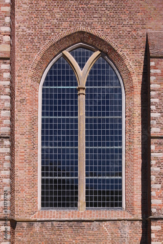 Texture of a simple gothic double window on the brick facade of Burgh-Haamstede village church in the Netherlands