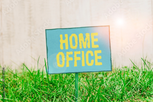Conceptual hand writing showing Home Office. Concept meaning space designated in a demonstrating s is residence for official business Plain paper attached to stick and placed in the grassy land photo