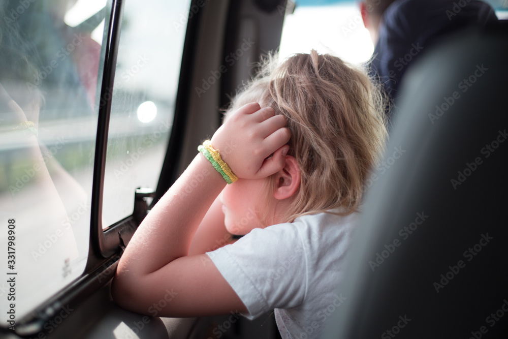 Little girl looks out the side window of the car Stock Photo | Adobe Stock