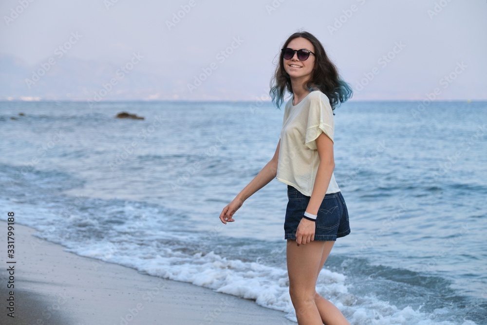 Trendy girl with blue hair in sunglasses walking along sea beach Trendy girl with blue hair in sunglasses walking along sea beach
