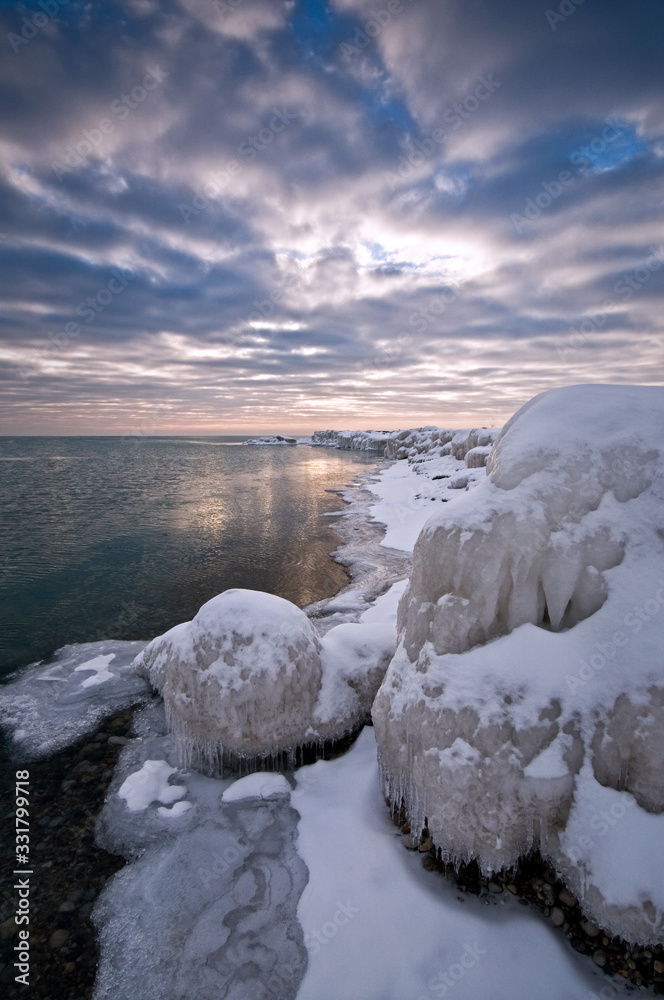 A dramatic winter sunrise over shoreline ice formations on Lake Michigan shoreline. A dramatic winter sunrise over shoreline ice formations on Lake Michigan shoreline.