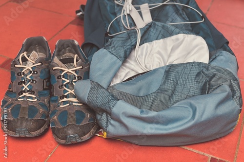 Hiking equipment: backpack and trekking boots on the floor. Horizontal photo and brown background. Tourist backgrounds and still-life. Preparation and planning for the travelling. Concept of the photo