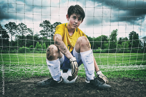 Φωτογραφία Male child soccer player sitting in the muddy goal