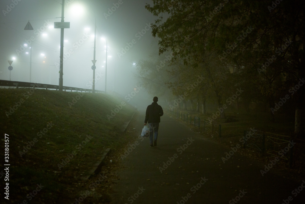 Lonely man at night in the fog in the city