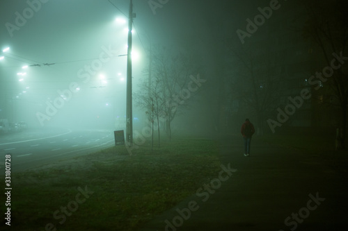 Lonely man at night in the fog in the city