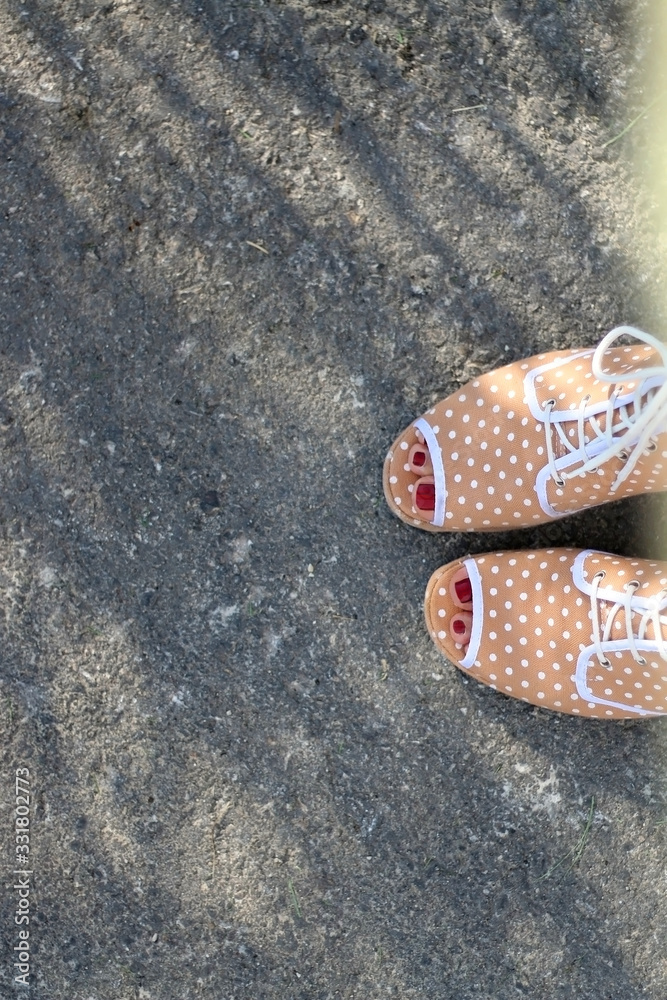 Fototapeta premium Unrecognizable person wearing quirky polka dot sandals. Top view. 