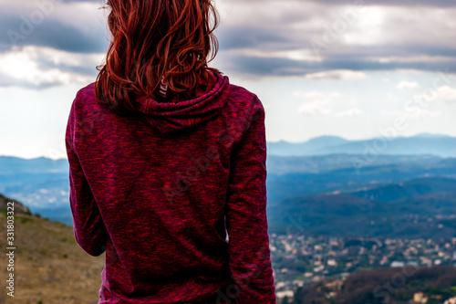 Canvas Print A back view shot of an unrecognizable  young redheaded woman standing enjoying t