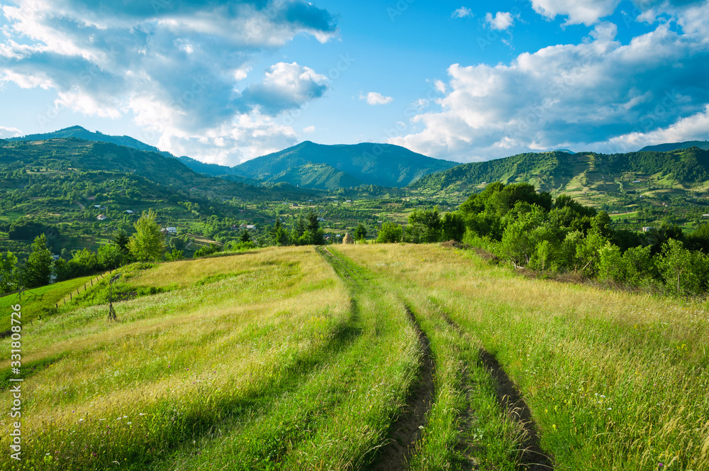 A peaceful landscape, green hills in spring time. A country road is cutting through the immaculate grass, illustrating the idea of travel , tourism or exploring