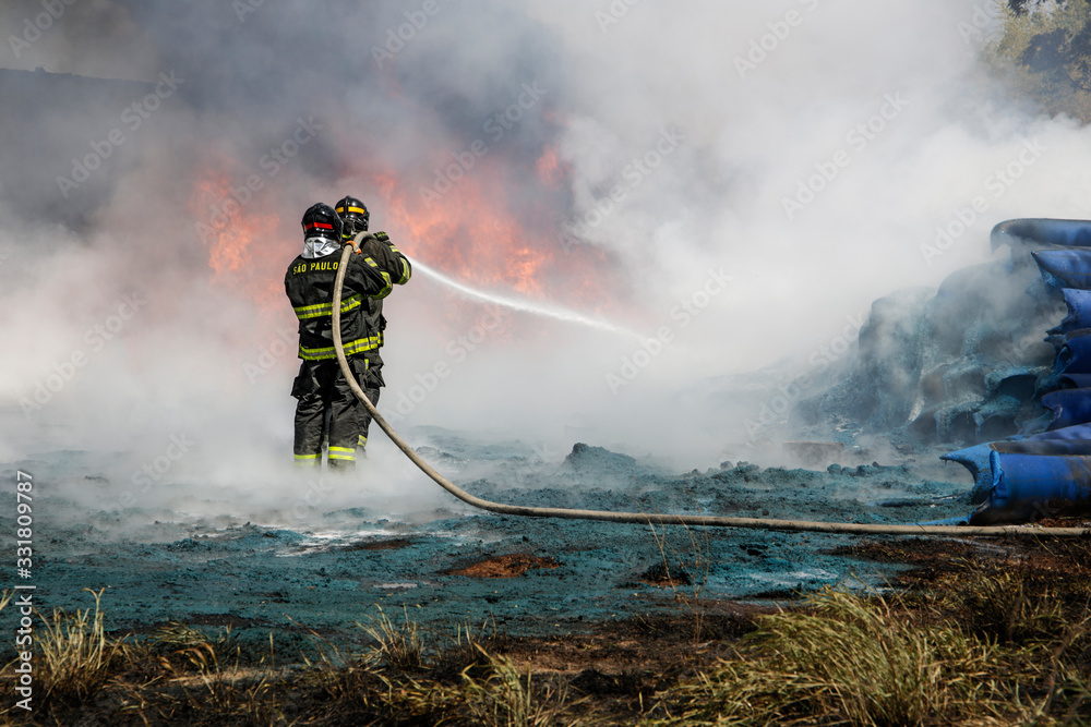 Obraz premium Two firefighters containing the flames