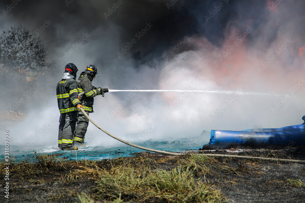 Obraz premium Two firefighters containing the flames