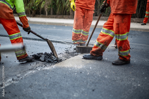 Workers sweeping asphalt
