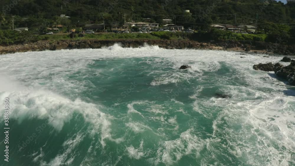 The rough waves of the Pacific Ocean crashing into the rocky coastline of Oahu in the Hawaiian Islands with the camera moving backwards.