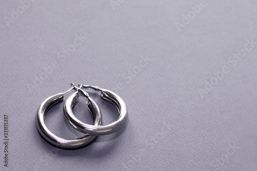 Tablou pe pânză Large silver hoop rings in the lower left corner on a gray background close-up