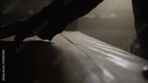 Mann arbeitet mit Holzbrettern in einer staubigen Werkstatt