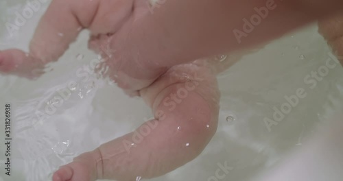 View of newborn legs swimming in water during bathing