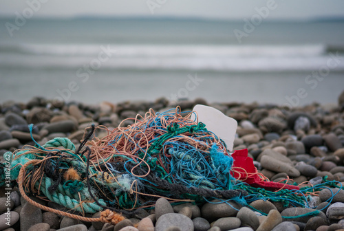 Fotografie Old fishing nets and plastic waste washed up on the shore of the west coast of I