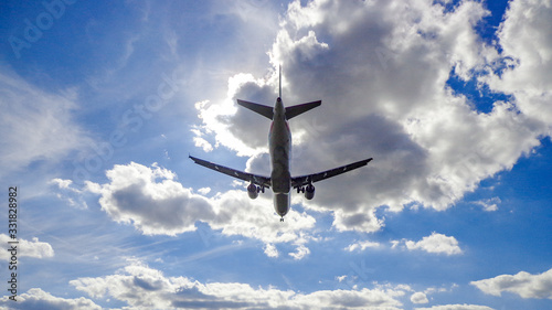 Low-Angle View of Commercial Aircraft Soaring Overhead with Clouds Above