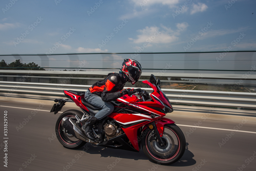 Biker in helmet and gear biking a motorcycle on the bridge