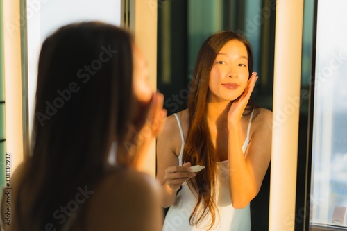 Portrait beautiful young asian woman apply cream on her face and facial in bathroom