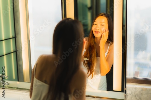 Portrait beautiful young asian woman apply cream on her face and facial in bathroom