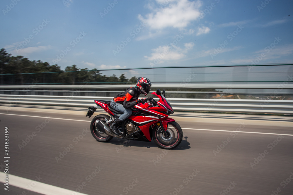 Biker in helmet and gear biking a motorcycle on the bridge under the blue sky