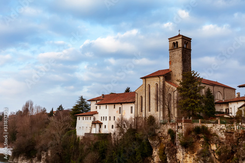 Chiesa e abitazione a dirupo sul fiume Natisone a Cividale del Friuli, Udine, Italia. Nuvolosa giornata con vegetazione spontanea.