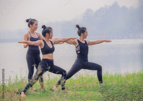 Cute and beautiful Asian women are practicing yoga by the lake.