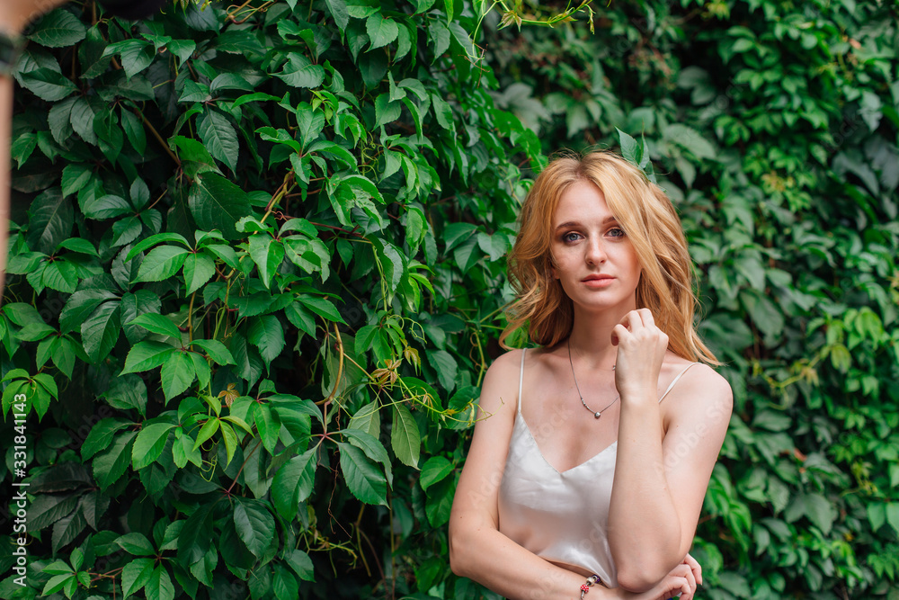 Portrait of a young beautiful woman, standing next to the wall of wild grape leaves. Portrait of a young beautiful woman, standing next to the wall of wild grape leaves.