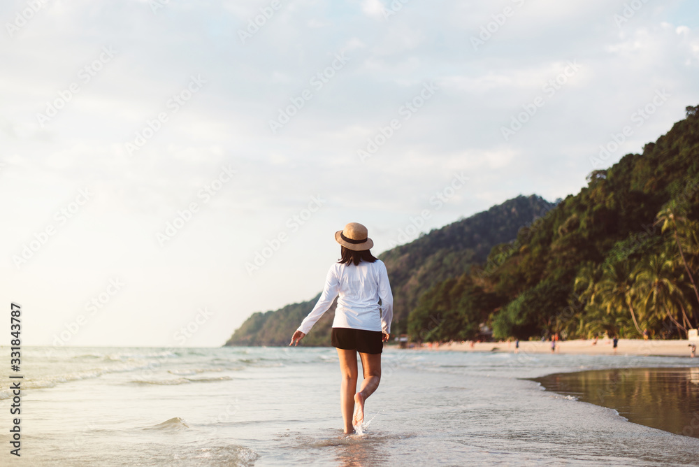 Happy asian woman walking on the beach near sea while beautiful sunset time,Relaxing and enjoying concept Happy asian woman walking on the beach near sea while beautiful sunset time,Relaxing and enjoying concept
