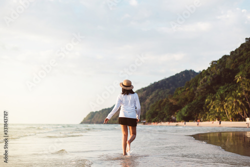 Happy asian woman walking on the beach near sea while beautiful sunset time,Relaxing and enjoying concept