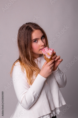 vertical portrait of a pretty teenager girl who eats flowers ice cream