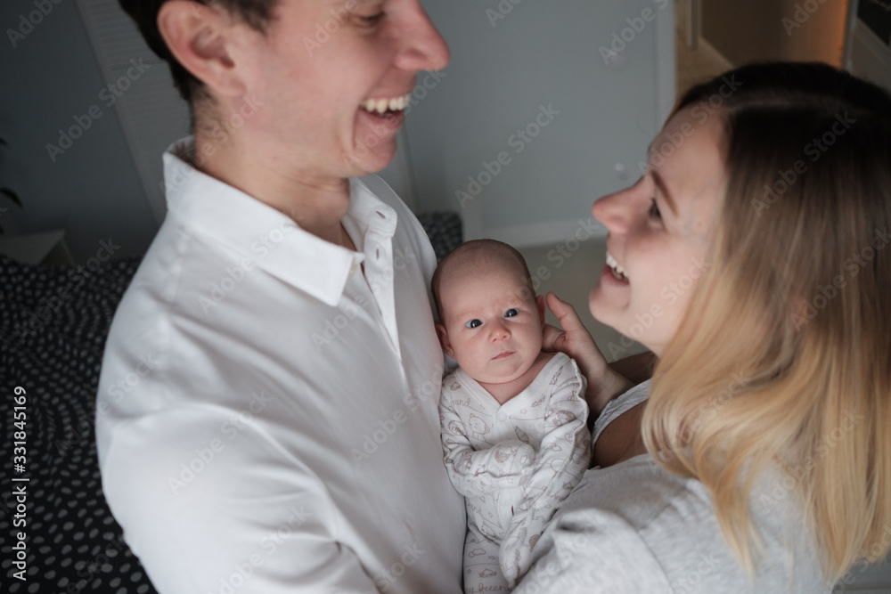 Smiling mother and father holding their newborn baby daughter at home Smiling mother and father holding their newborn baby daughter at home