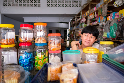 Asian Indonesian women in front of small local family-owned business store, locally called warung. Selective Focus.
