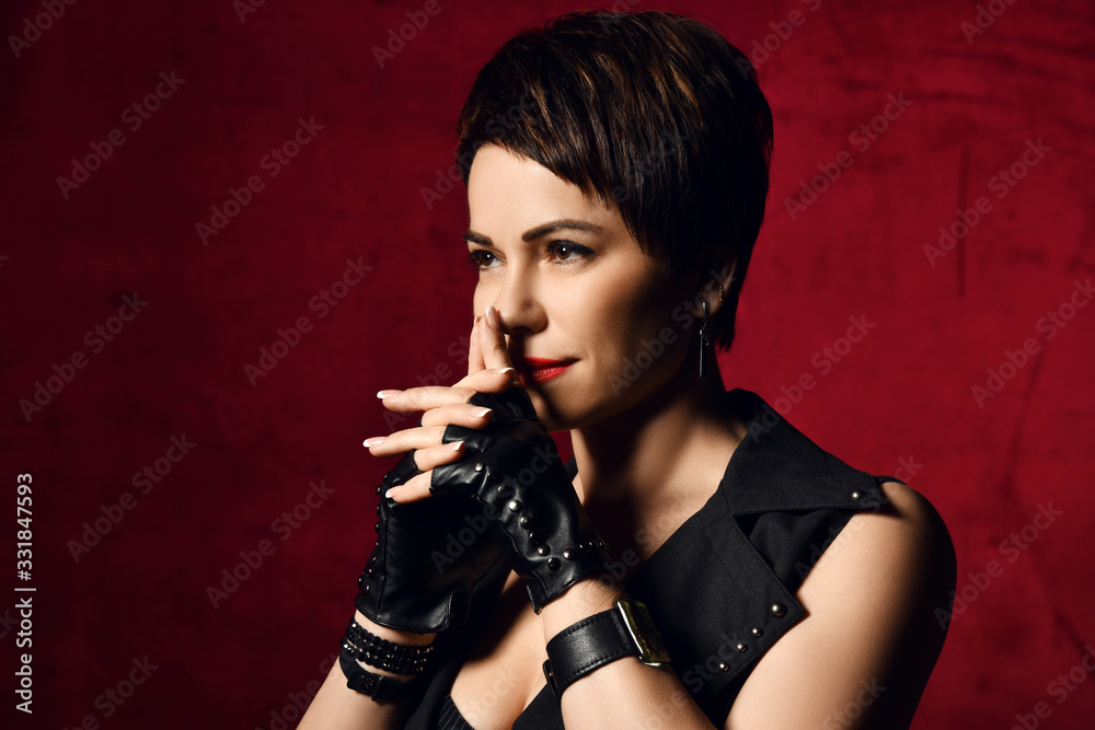 Portrait of brunette woman in leather gloves with cut fingers holding her interlocked fingers at face watching thinking Portrait of brunette woman in leather gloves with cut fingers holding her interlocked fingers at face watching thinking