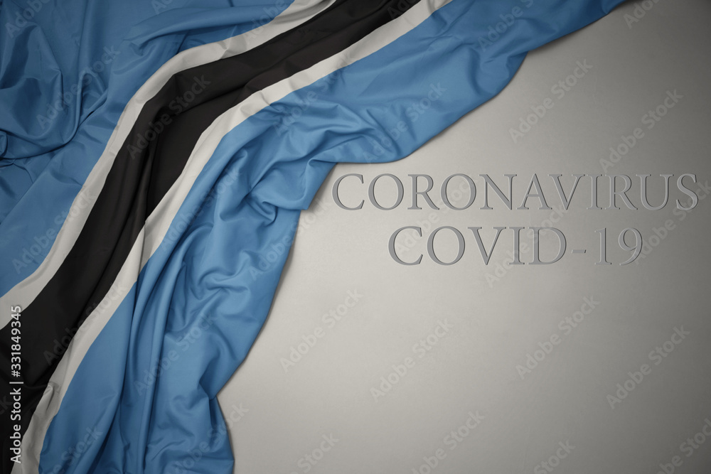 waving national flag of botswana on a gray background with text coronavirus covid-19 . concept.