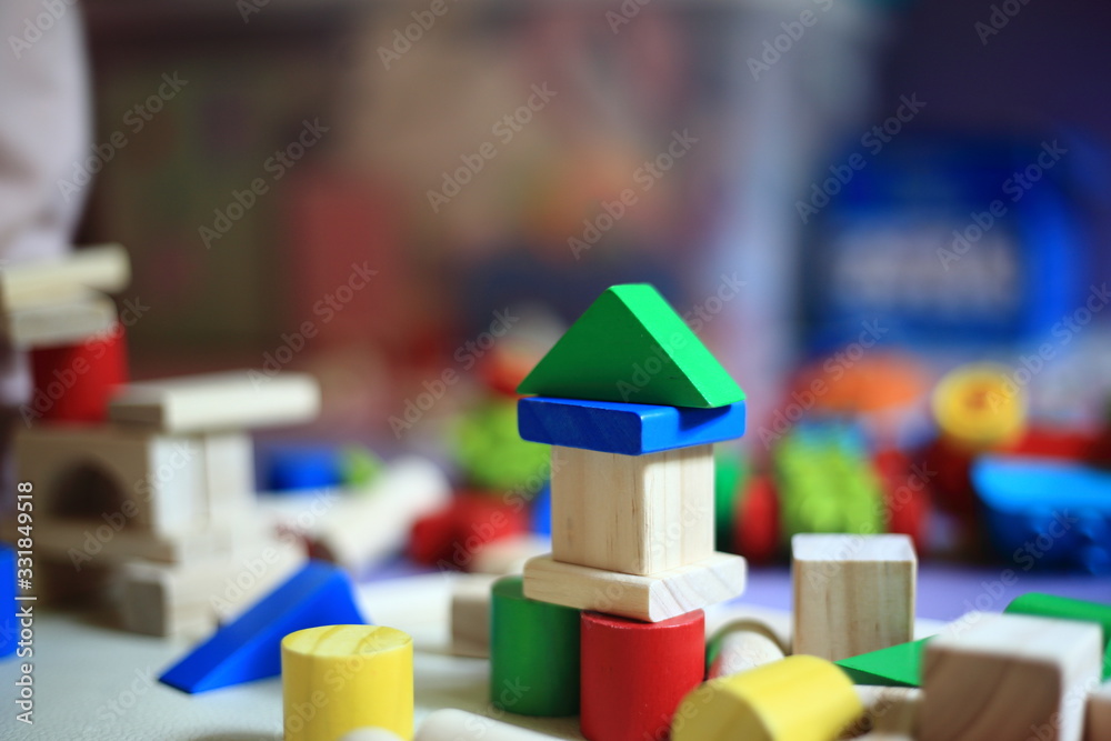 baby toy, wood blocks making into shape and form. blurred baby playing in the background. children development and play learn concepts. baby toy, wood blocks making into shape and form. blurred baby playing in the background. children development and play learn concepts.