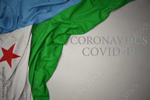waving national flag of djibouti on a gray background with text coronavirus covid-19 . concept.