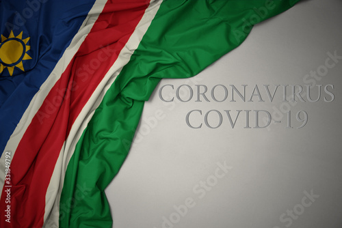 waving national flag of namibia on a gray background with text coronavirus covid-19 . concept.
