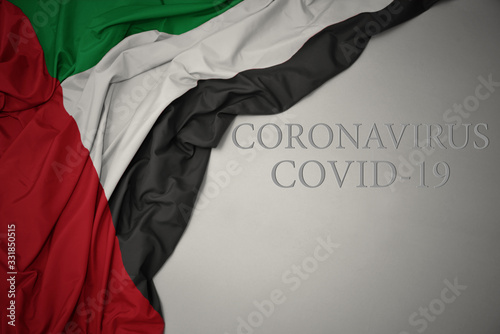 waving national flag of united arab emirates on a gray background with text coronavirus covid-19 . concept.
