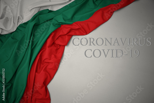 waving national flag of bulgaria on a gray background with text coronavirus covid-19 . concept.